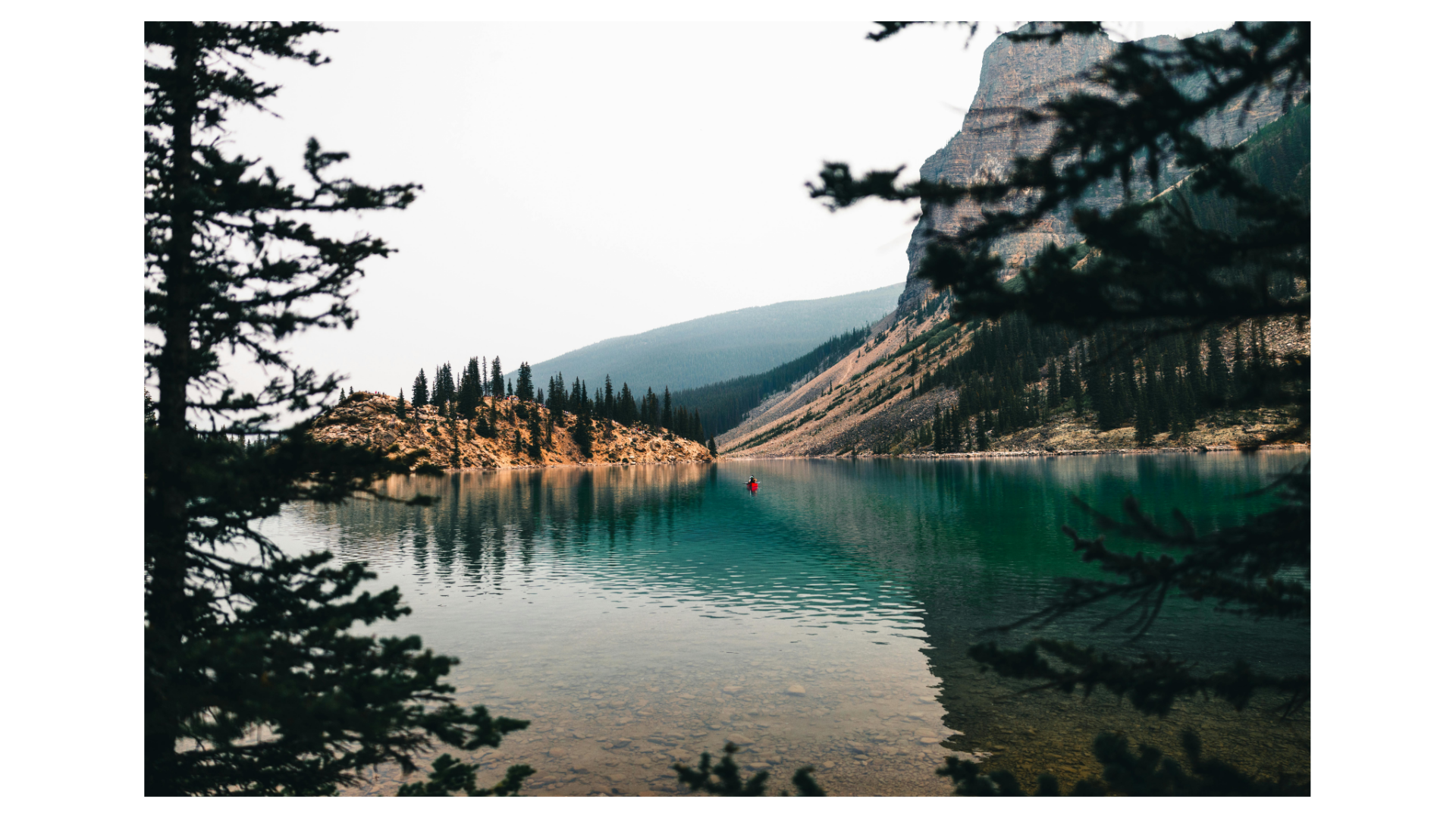 A single canoe on a calm mountain lake, framed by evergreens and cliffs, representing the clarity and guidance needed to build a referral system