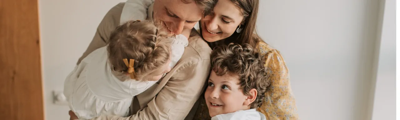 A family of four embracing in a bright room, the kind of household simplified issue life insurance is designed to protect